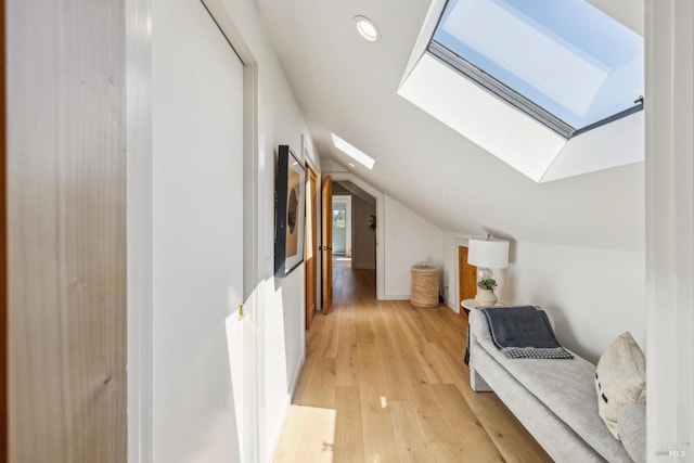 hall featuring recessed lighting, light wood finished floors, and lofted ceiling with skylight