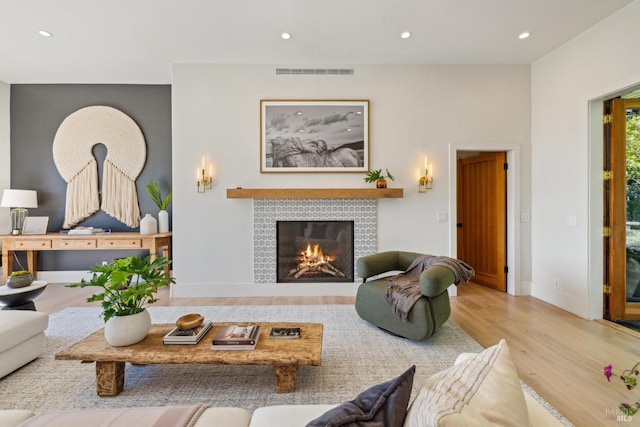 living area with a fireplace, recessed lighting, wood finished floors, and visible vents