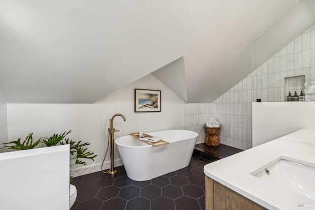 full bath with tile patterned flooring, a freestanding tub, tile walls, and vaulted ceiling