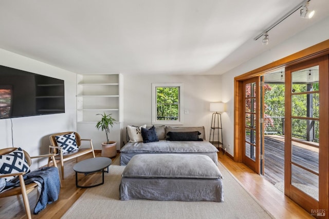 bedroom featuring baseboards, access to outside, rail lighting, and wood finished floors