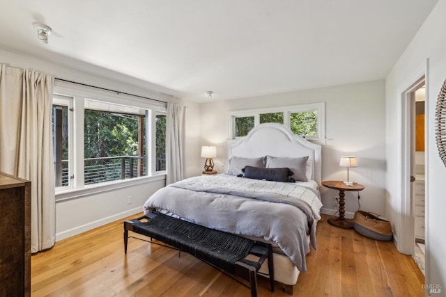 bedroom featuring baseboards, multiple windows, and wood-type flooring
