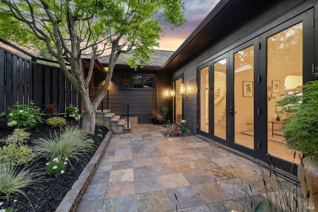 patio terrace at dusk featuring fence and french doors