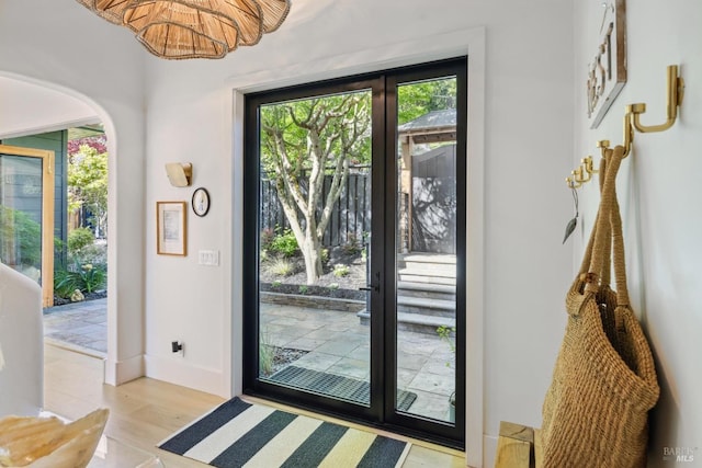 doorway with french doors, baseboards, a chandelier, and light wood-type flooring