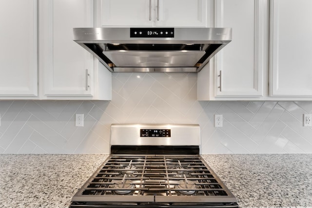 kitchen featuring stainless steel range with gas stovetop, white cabinets, tasteful backsplash, wall chimney range hood, and light stone counters