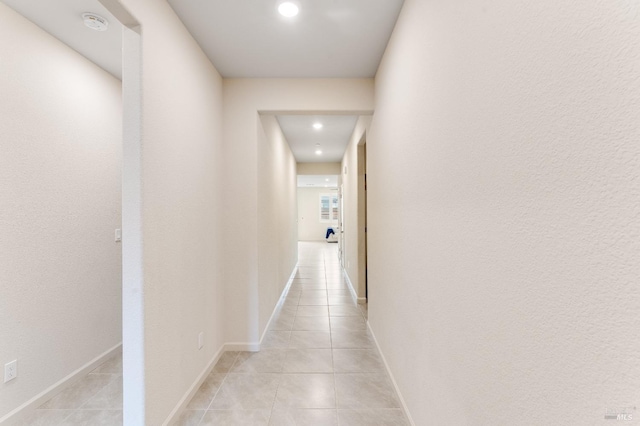 corridor featuring baseboards, light tile patterned flooring, and recessed lighting