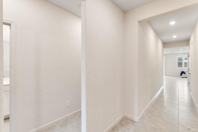 hallway featuring baseboards, recessed lighting, and light tile patterned flooring