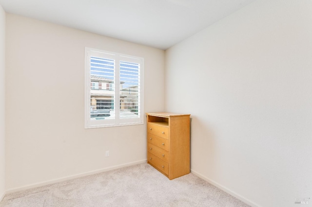 unfurnished room featuring baseboards and light colored carpet