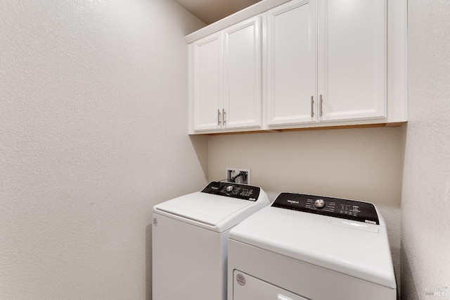 laundry area featuring separate washer and dryer, cabinet space, and a textured wall