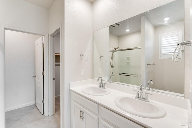 full bathroom with a sink, double vanity, a shower stall, and tile patterned floors