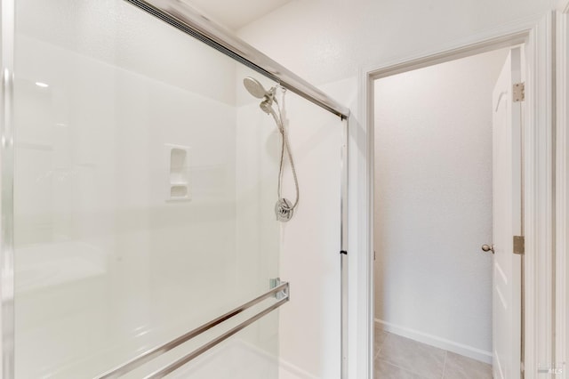 full bath with a stall shower, tile patterned flooring, and baseboards