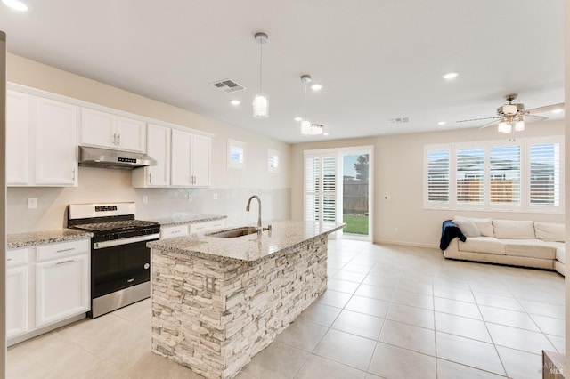 kitchen featuring a sink, visible vents, under cabinet range hood, gas stove, and white cabinets