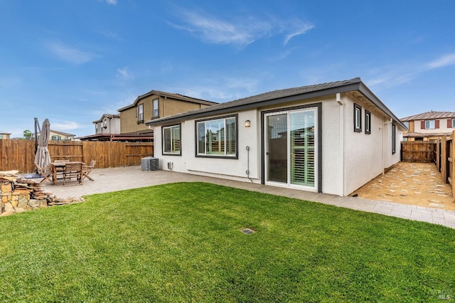 back of property with a patio area, central AC, a yard, stucco siding, and a fenced backyard