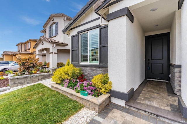 doorway to property featuring stucco siding and a lawn