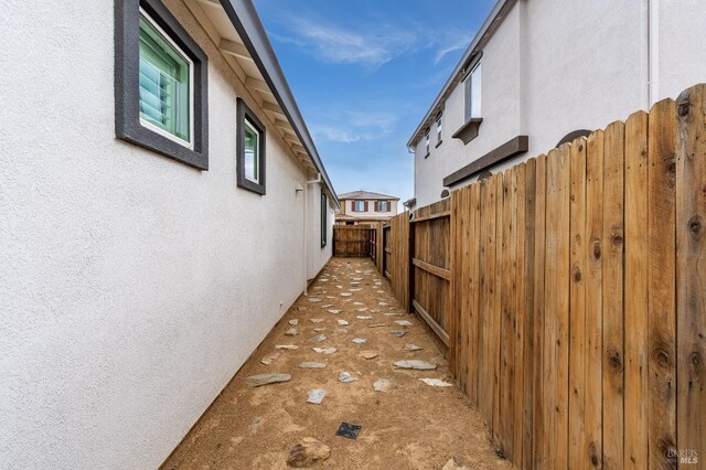 view of side of home with stucco siding and fence