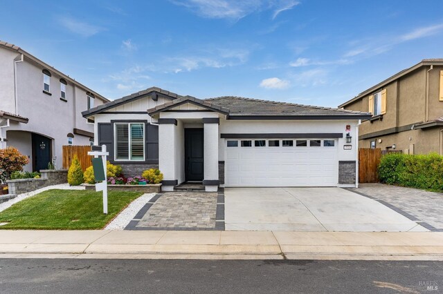 view of front of property featuring concrete driveway, fence, a garage, and stone siding