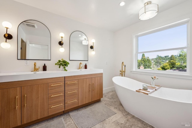 full bath with a sink, double vanity, baseboards, visible vents, and a soaking tub