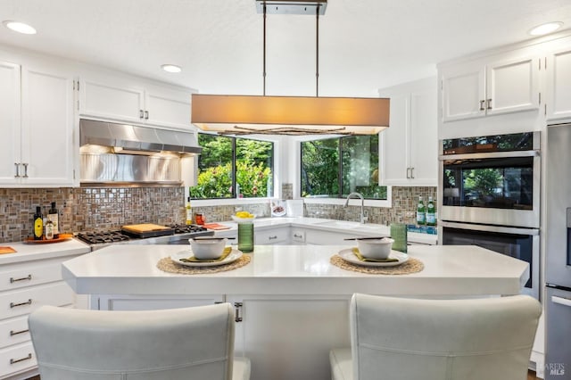 kitchen with light countertops, white cabinets, tasteful backsplash, a sink, and stainless steel appliances