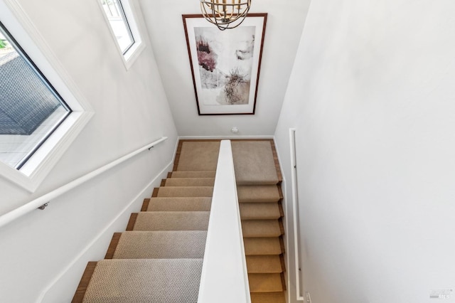 staircase with baseboards and a notable chandelier