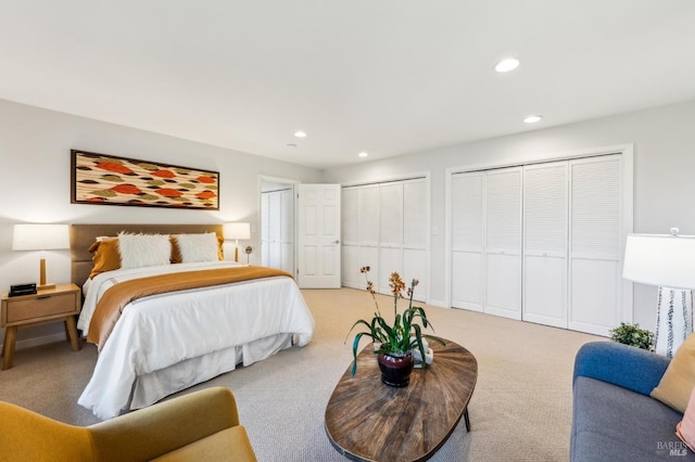 bedroom featuring multiple closets, recessed lighting, and light colored carpet