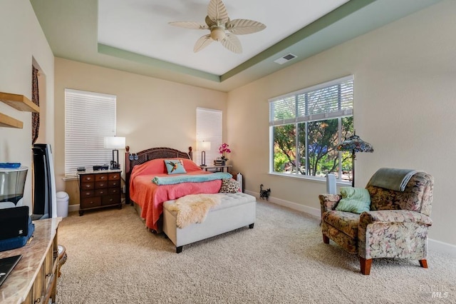 bedroom featuring a ceiling fan, visible vents, light carpet, and a raised ceiling