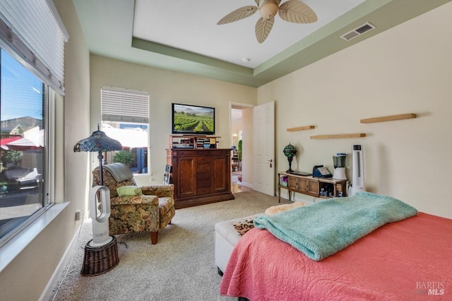 bedroom featuring a raised ceiling, carpet, a ceiling fan, baseboards, and visible vents