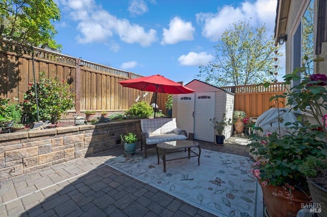 view of patio with a storage shed, an outbuilding, and a fenced backyard