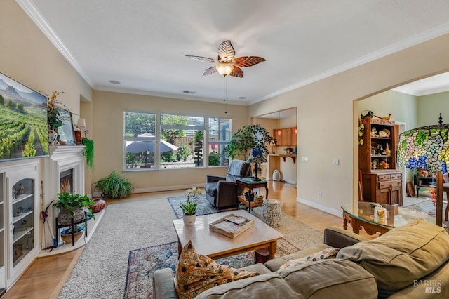living area with light wood-style floors, crown molding, and ceiling fan