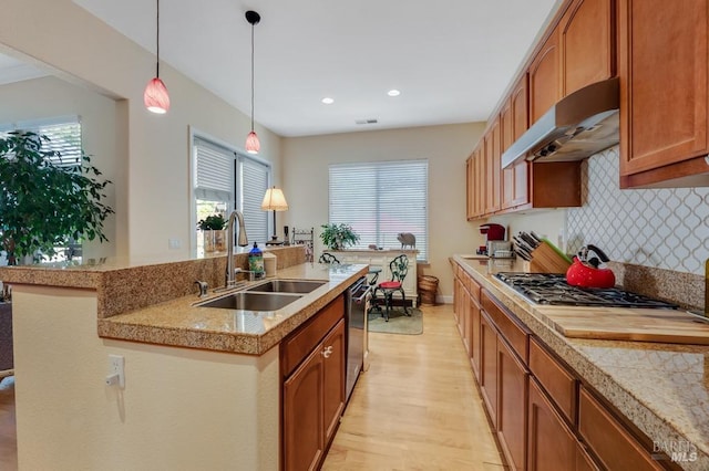 kitchen featuring a kitchen island with sink, light wood-style floors, under cabinet range hood, a sink, and stainless steel appliances