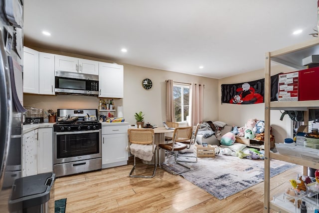 kitchen with appliances with stainless steel finishes, light wood finished floors, light countertops, white cabinetry, and recessed lighting