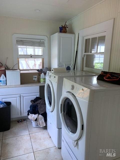 laundry room with washing machine and clothes dryer, plenty of natural light, light tile patterned floors, and cabinet space