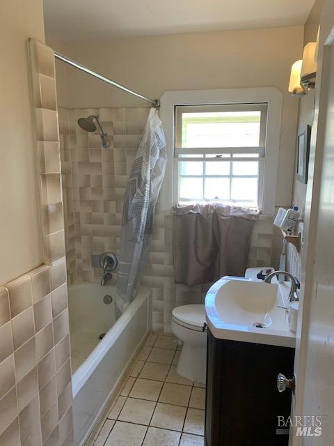 bathroom featuring vanity, tile patterned floors, toilet, and shower / bath combo with shower curtain