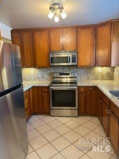 kitchen featuring light countertops, stainless steel appliances, light tile patterned flooring, and backsplash