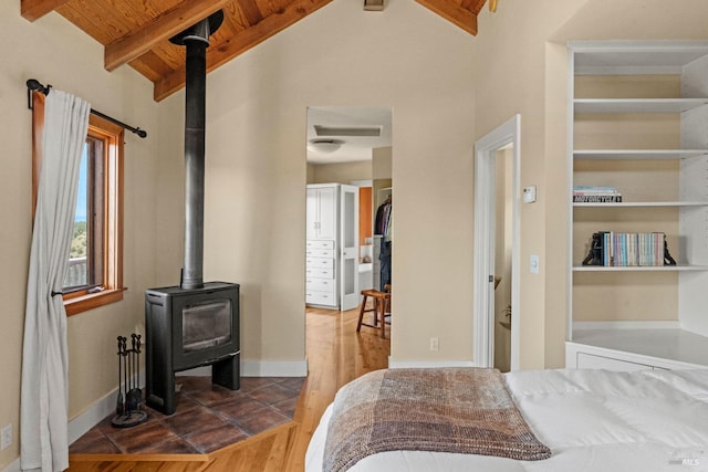 bedroom with wood ceiling, lofted ceiling with beams, wood finished floors, and a wood stove