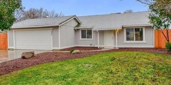 single story home featuring fence, a garage, board and batten siding, a front yard, and driveway