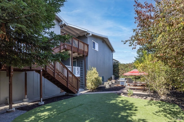 view of home's exterior featuring a balcony, a yard, and stairway