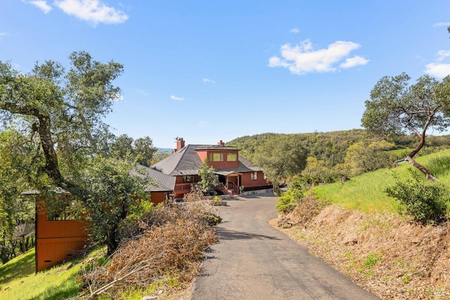 log home with driveway and a chimney