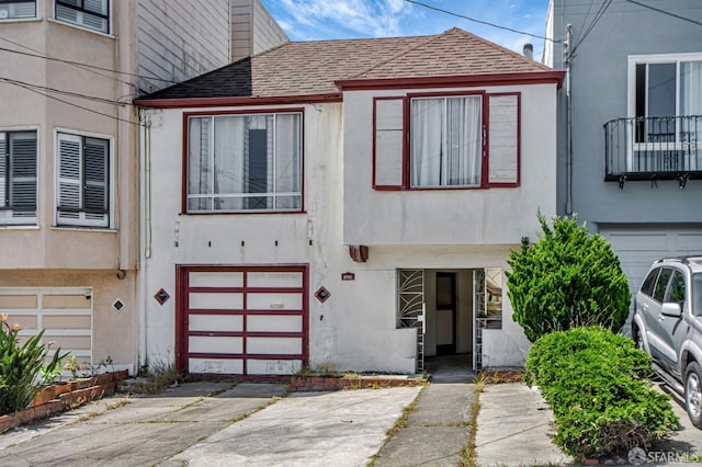 townhome / multi-family property with an attached garage, roof with shingles, and stucco siding