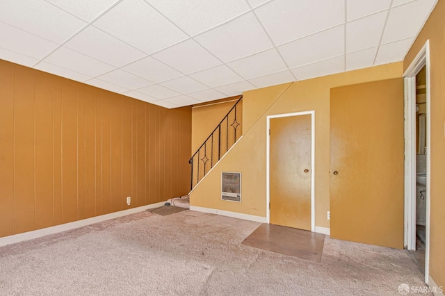 basement featuring carpet floors, a drop ceiling, and stairs