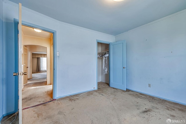 unfurnished bedroom with arched walkways, ornamental molding, baseboards, and carpet flooring