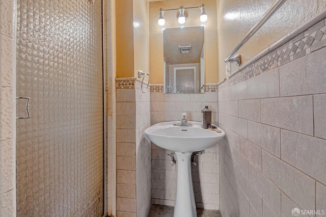 bathroom featuring visible vents, a sink, wainscoting, and tile walls