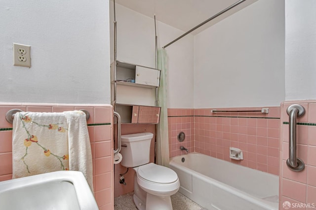 bathroom with tile walls, wainscoting, toilet, and speckled floor