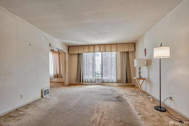 empty room featuring crown molding, carpet, and visible vents