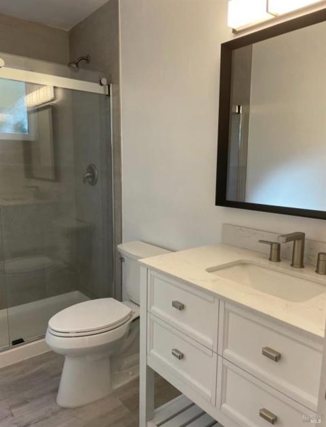 full bathroom with vanity, toilet, wood finished floors, and a stall shower