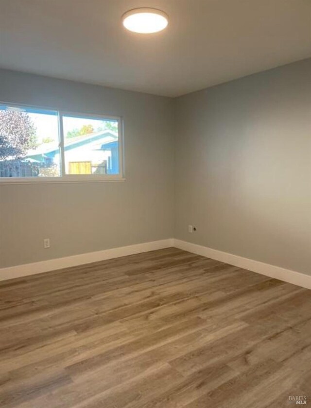 empty room with baseboards and wood finished floors