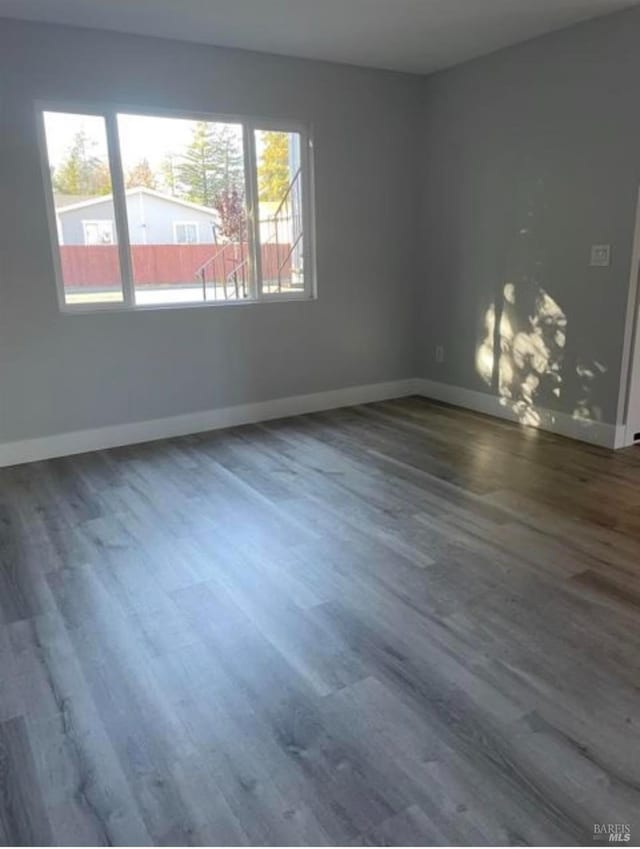 empty room with baseboards, plenty of natural light, and wood finished floors