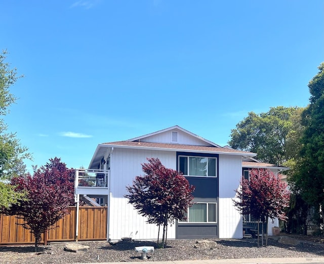 view of side of home featuring fence and a balcony