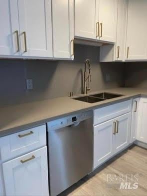 kitchen featuring light countertops, white cabinetry, a sink, light wood finished floors, and dishwasher