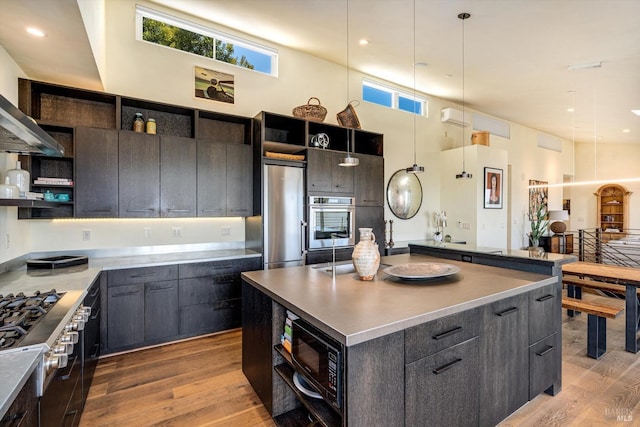 kitchen with open shelves, pendant lighting, light wood-style floors, a high ceiling, and stainless steel appliances