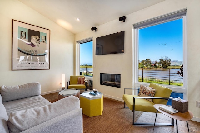 living area with plenty of natural light, baseboards, and a glass covered fireplace
