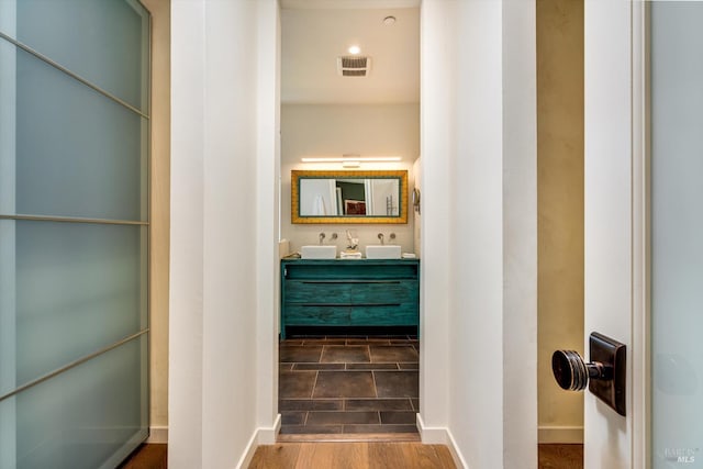 bathroom with baseboards, vanity, wood finished floors, and visible vents
